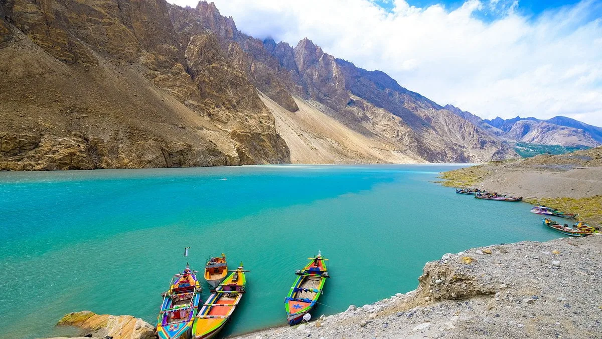 Colourful painted boats moored on the turquoise water of Attabad Lake, Upper Hunza, beneath steep Karakoram cliffs