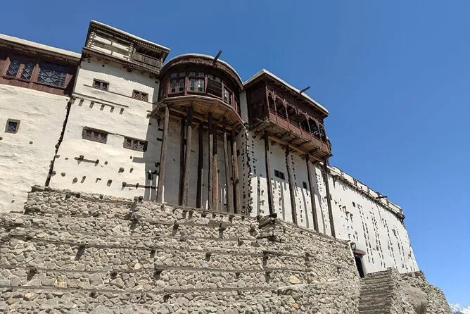 Baltit Fort in Karimabad, Hunza, its carved wooden balconies projecting over stone terraces against a blue sky