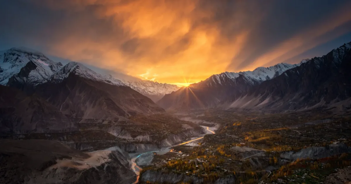 Hunza Valley at sunset with snow-capped Karakoram peaks glowing above the green valley