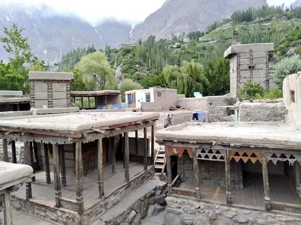Carved wooden mosques and watchtowers in the historic walled village of Ganish, Hunza, with green terraces behind