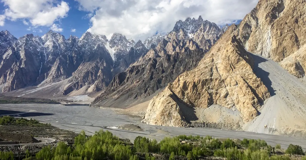 Puncak bergerigi Passu Cones (Tupopdan) menjulang di atas Sungai Hunza dan perkampungan hijau di sepanjang Lebuh Raya Karakoram, Gojal, Gilgit-Baltistan, Pakistan