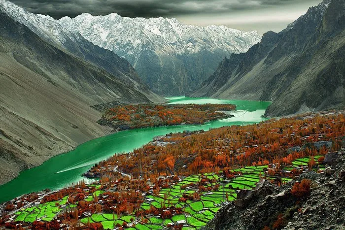 Green terraced fields and autumn poplars of Gulmit village in Gojal, Upper Hunza, above the emerald valley water