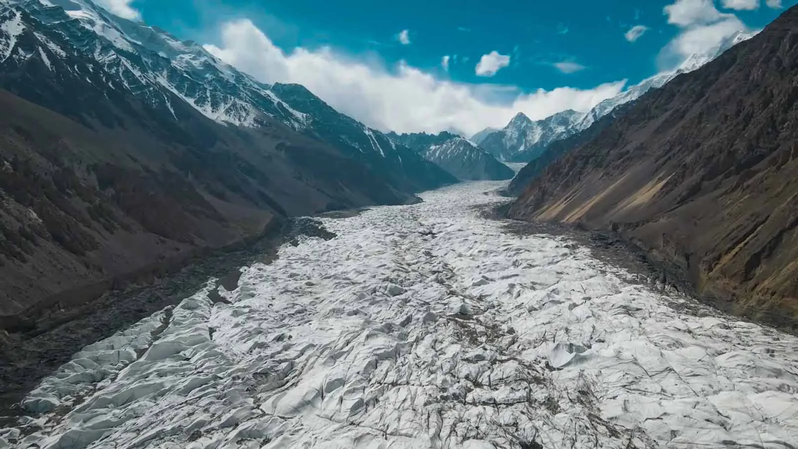 The cracked white tongue of the Passu Glacier snaking down the valley between snow peaks, Gojal, Upper Hunza