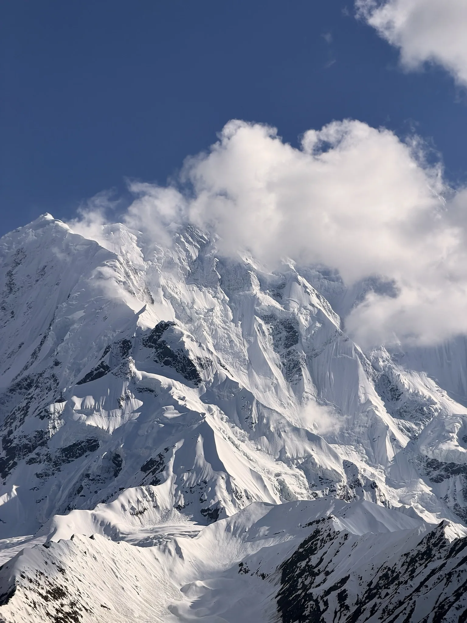 Snow-draped north face of Rakaposhi (7,788m) with clouds streaming off the summit