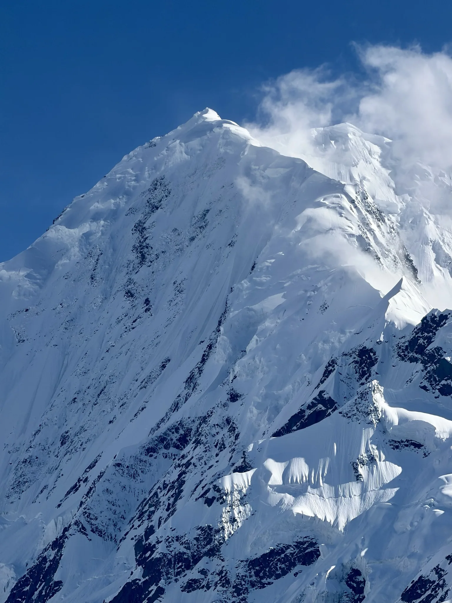 Close-up of Rakaposhi's snow-plastered summit ridge and hanging glaciers under a blue sky