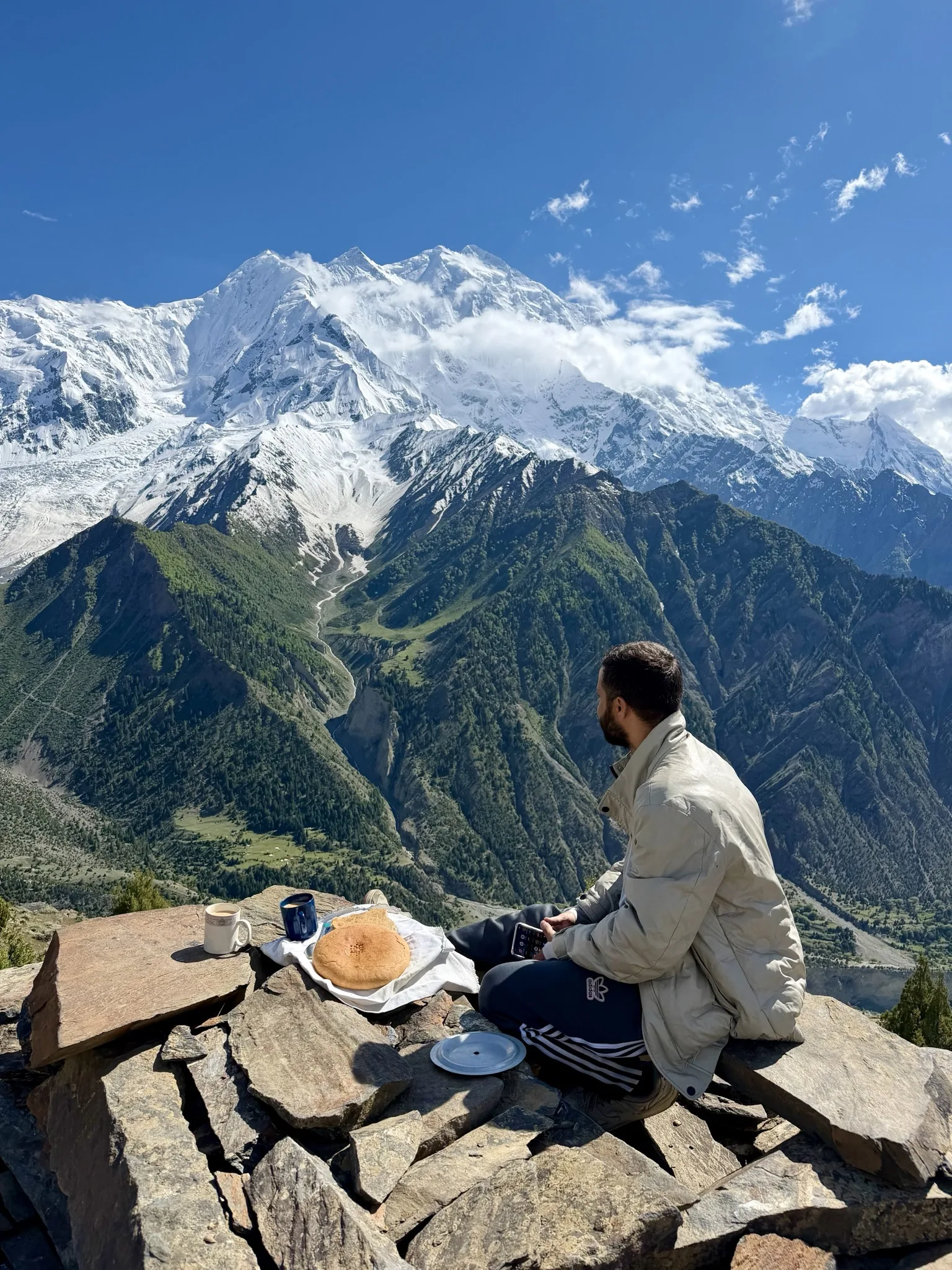 Trekker with tea and paratha breakfast at a Rakaposhi viewpoint above the Nagar Valley