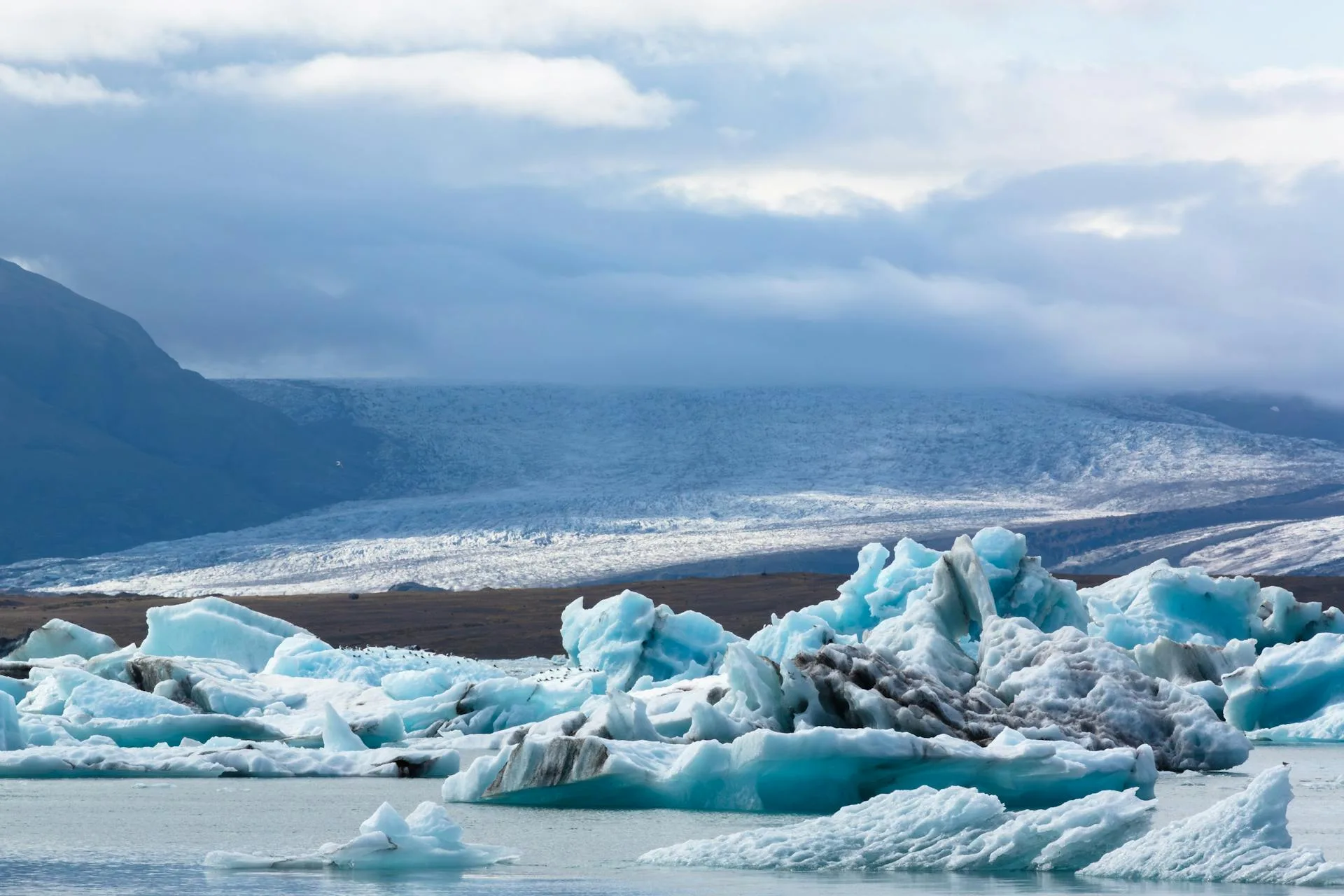 A glacier meeting a frozen lake in the mountains