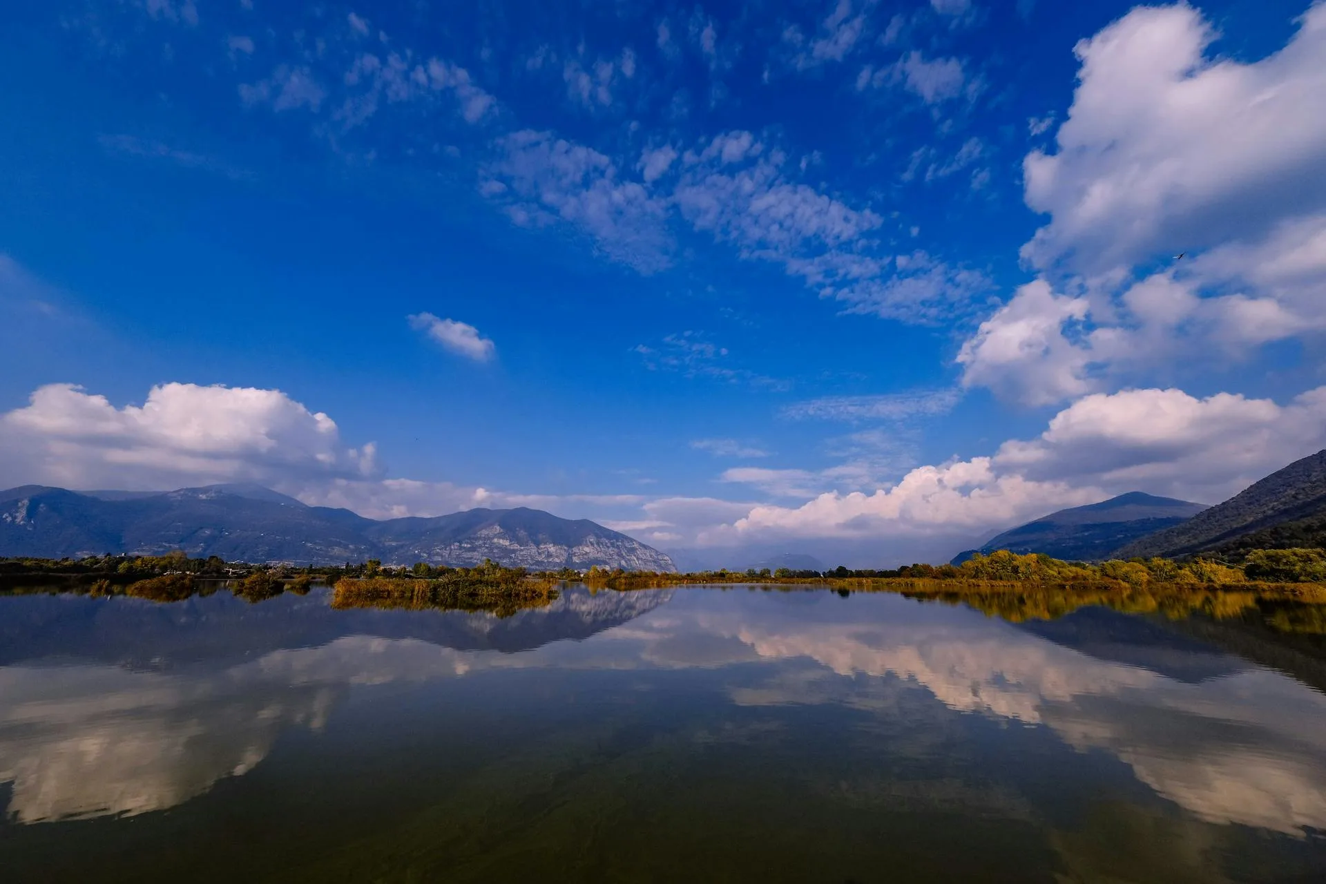 A calm lake reflecting mountains and blue sky