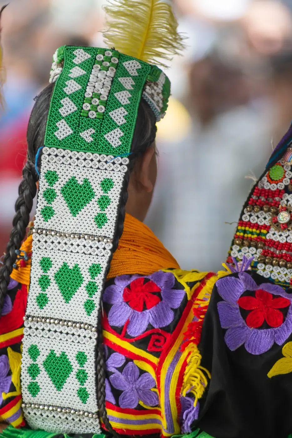 Bestickter Kopfschmuck und bunte Gewänder einer Kalash-Tänzerin beim Frühlingsfest