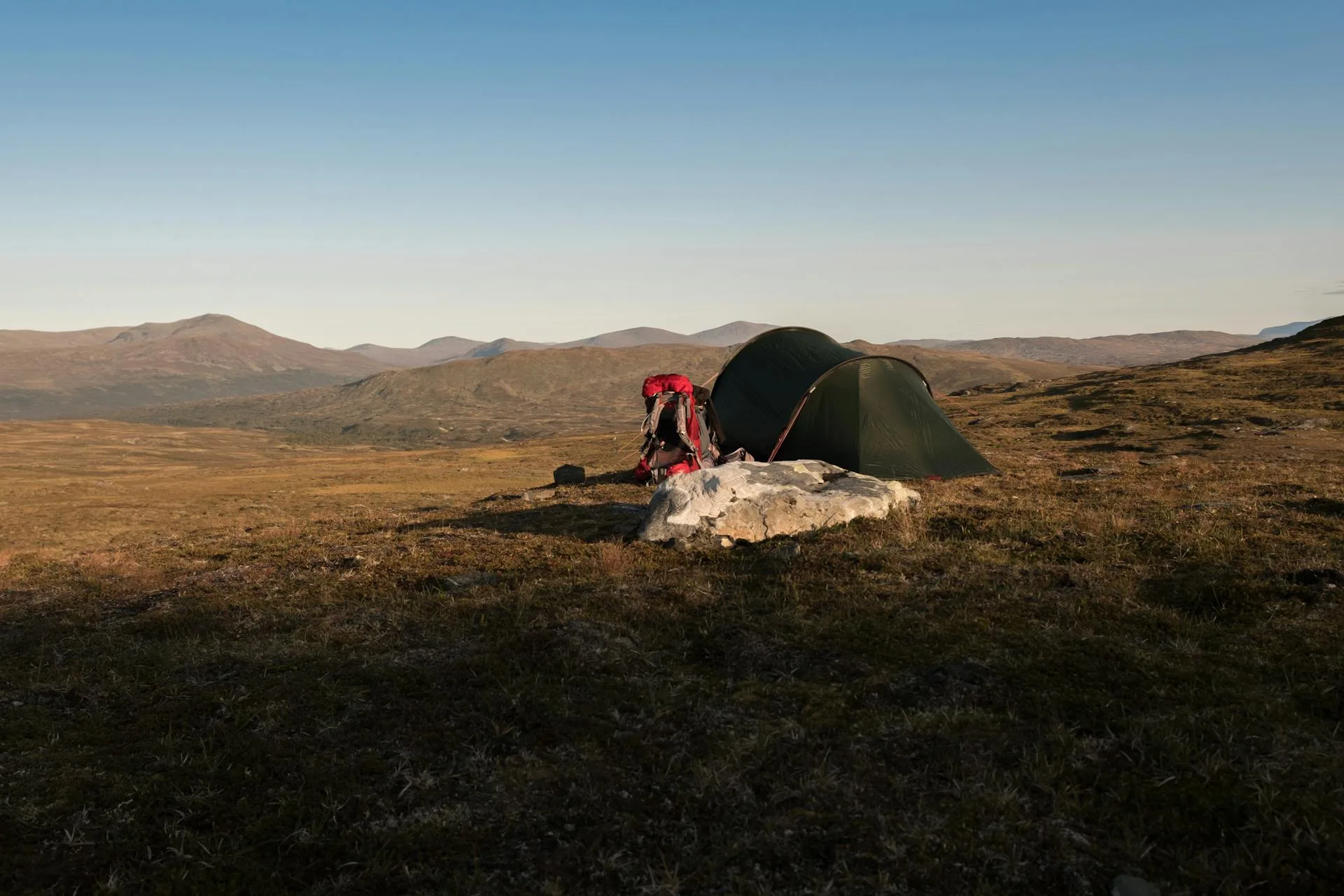 Camping tent on open grass field under blue sky
