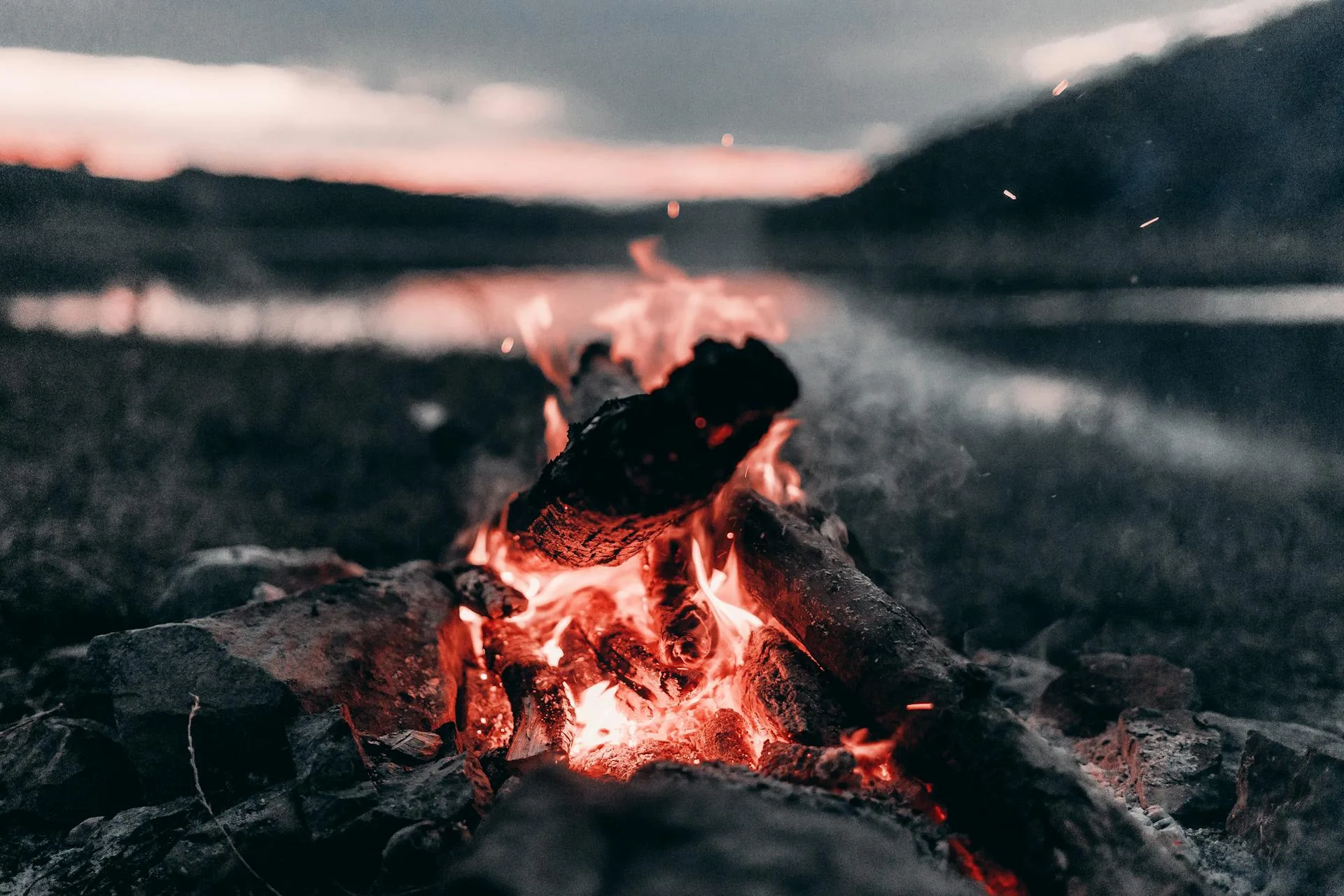 Bonfire near lake and mountains at night