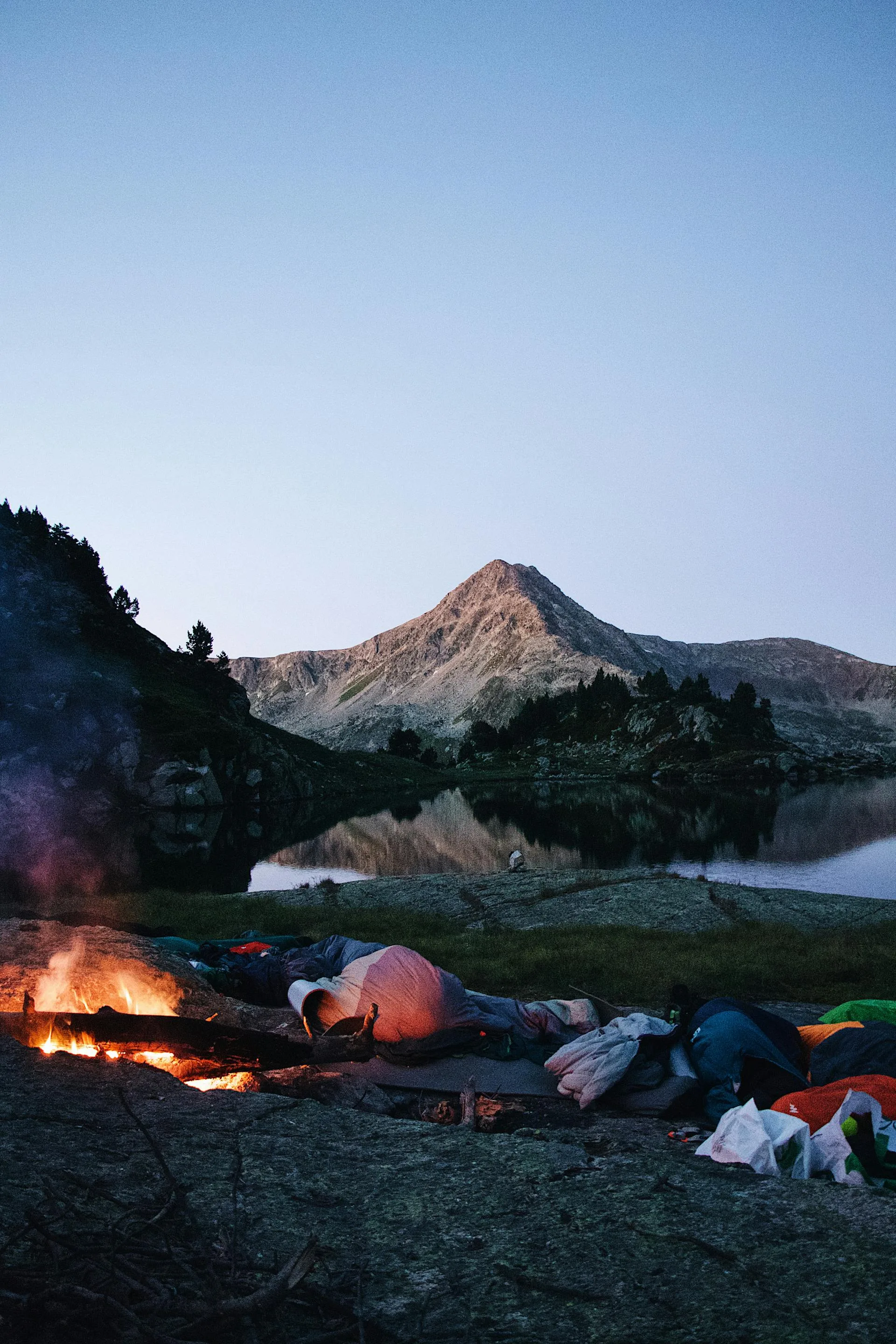 Tents around campfire with mountain peak