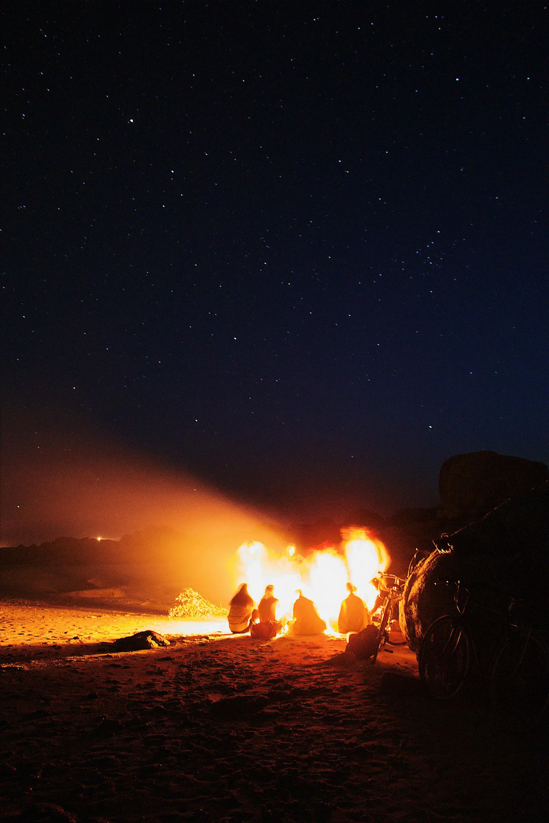 People around bonfire under starry night sky