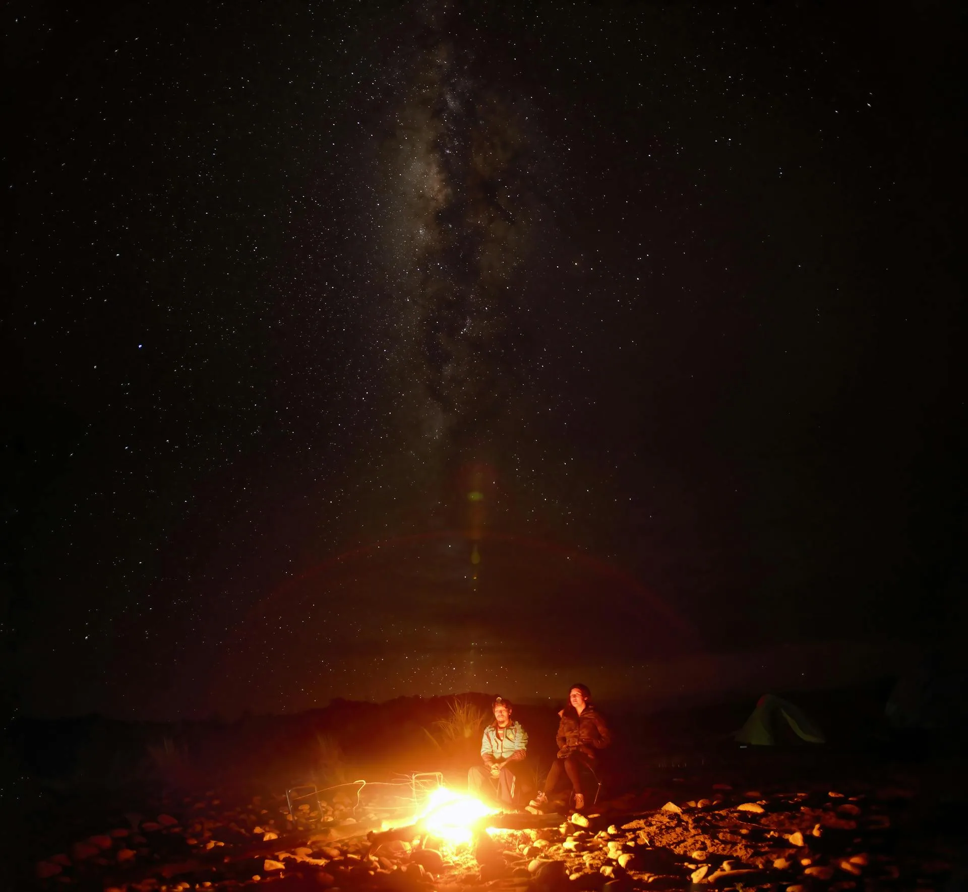 People enjoying campfire under Milky Way