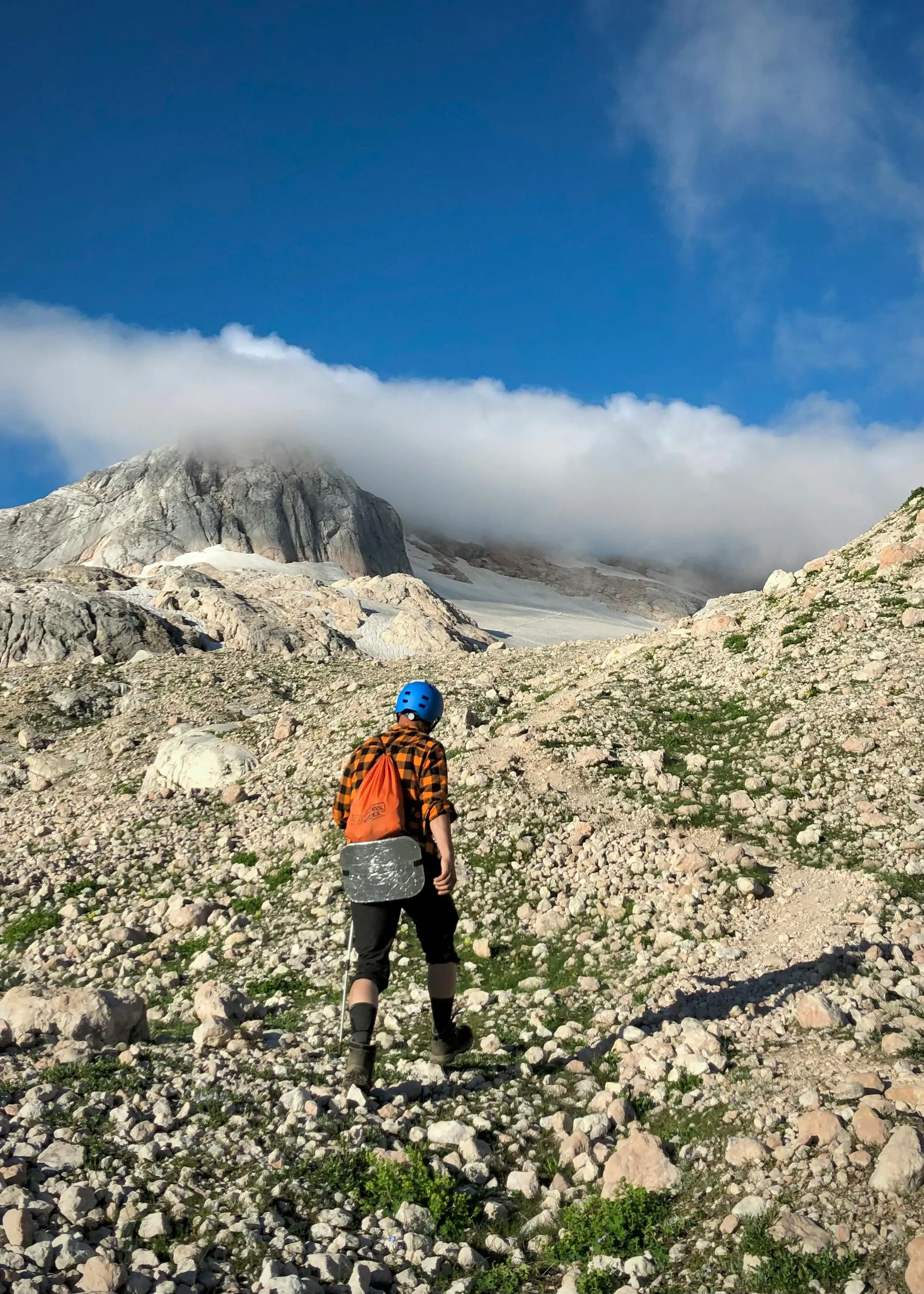 A hiker trekking up a rocky mountain trail