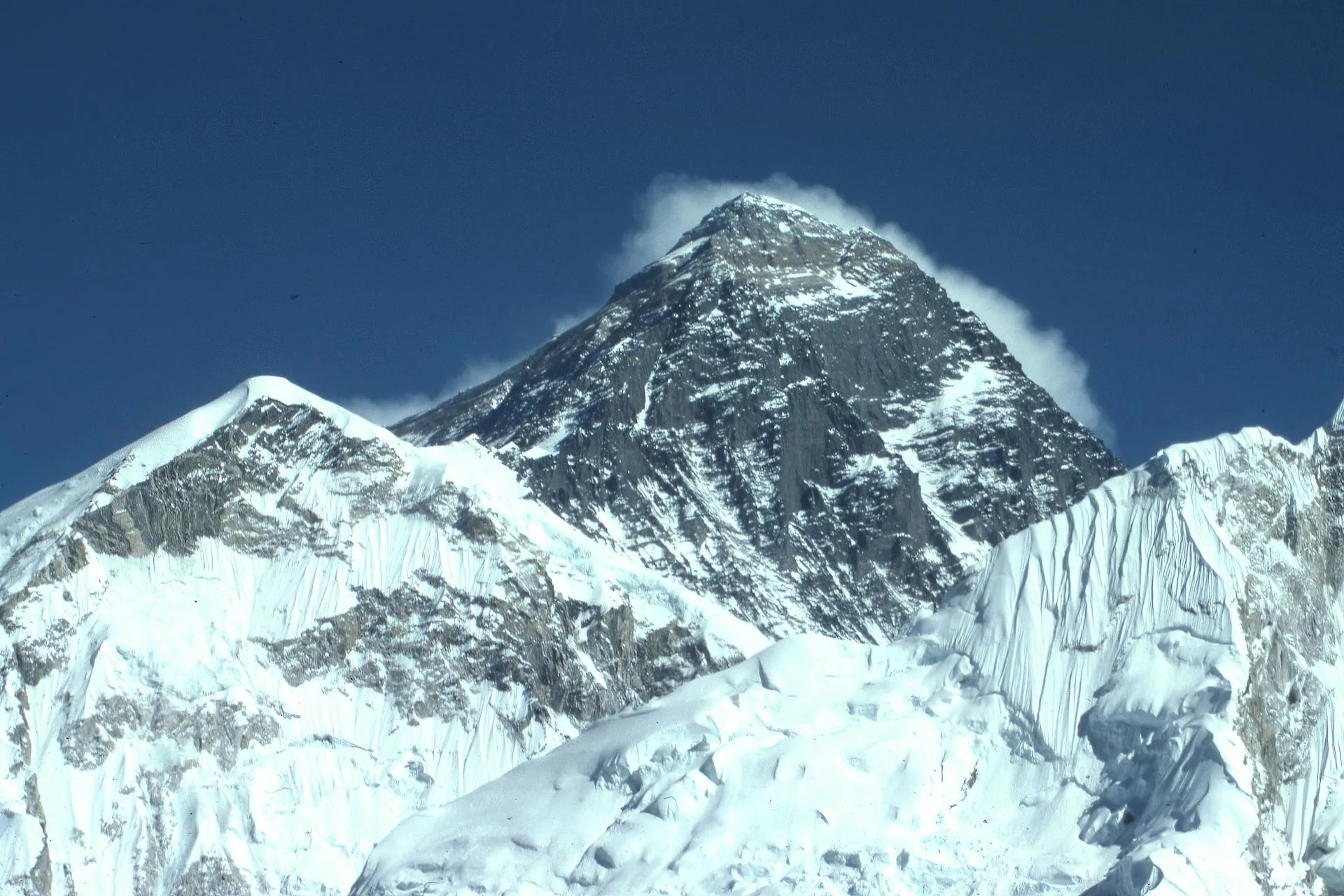 A towering snow-capped mountain peak under clear blue sky