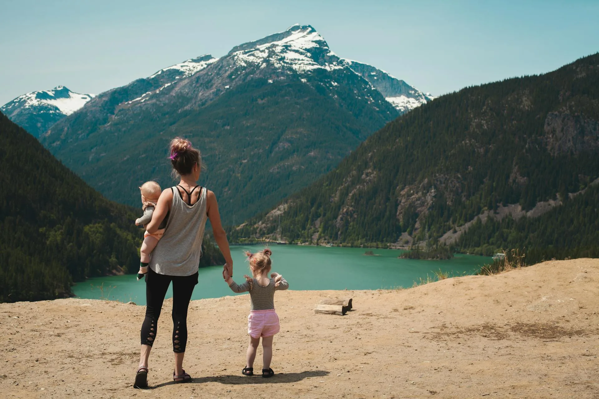 Mother and children walking near mountain lake