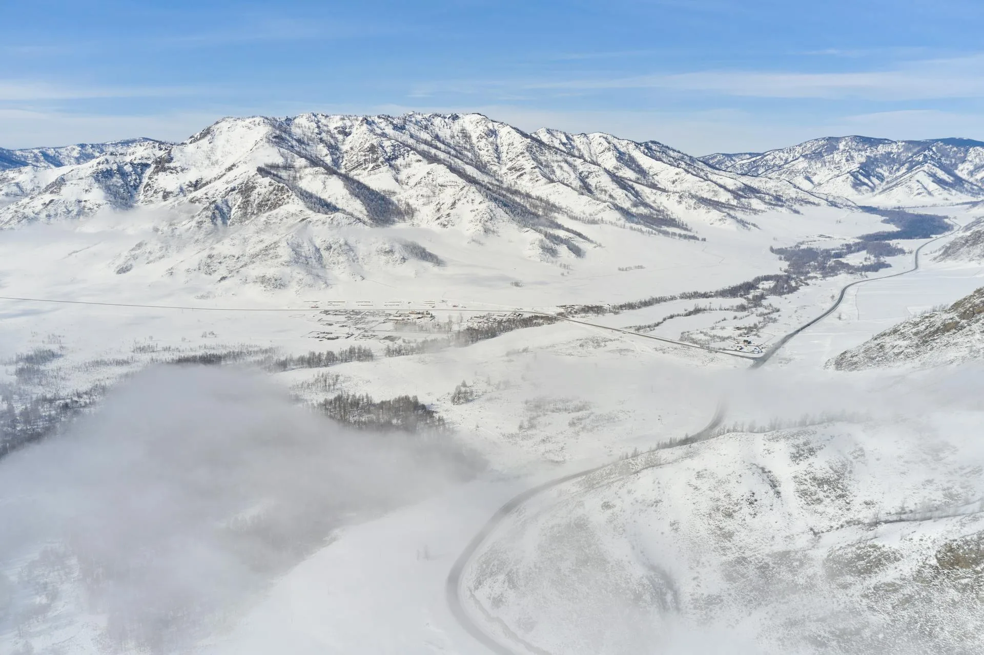 Snowy road and river through mountain valley