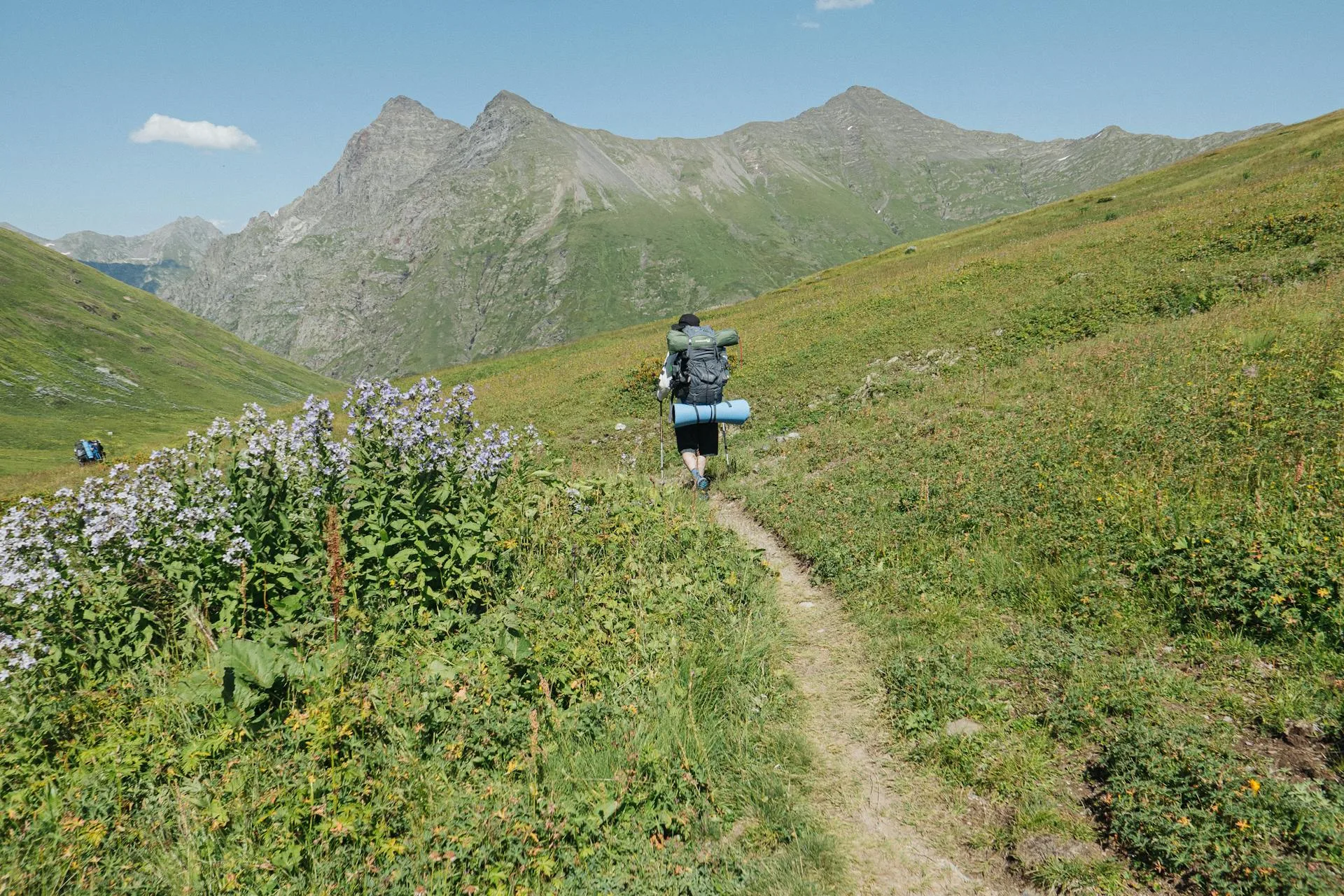 A trekker carrying a backpack on a mountain hiking trail