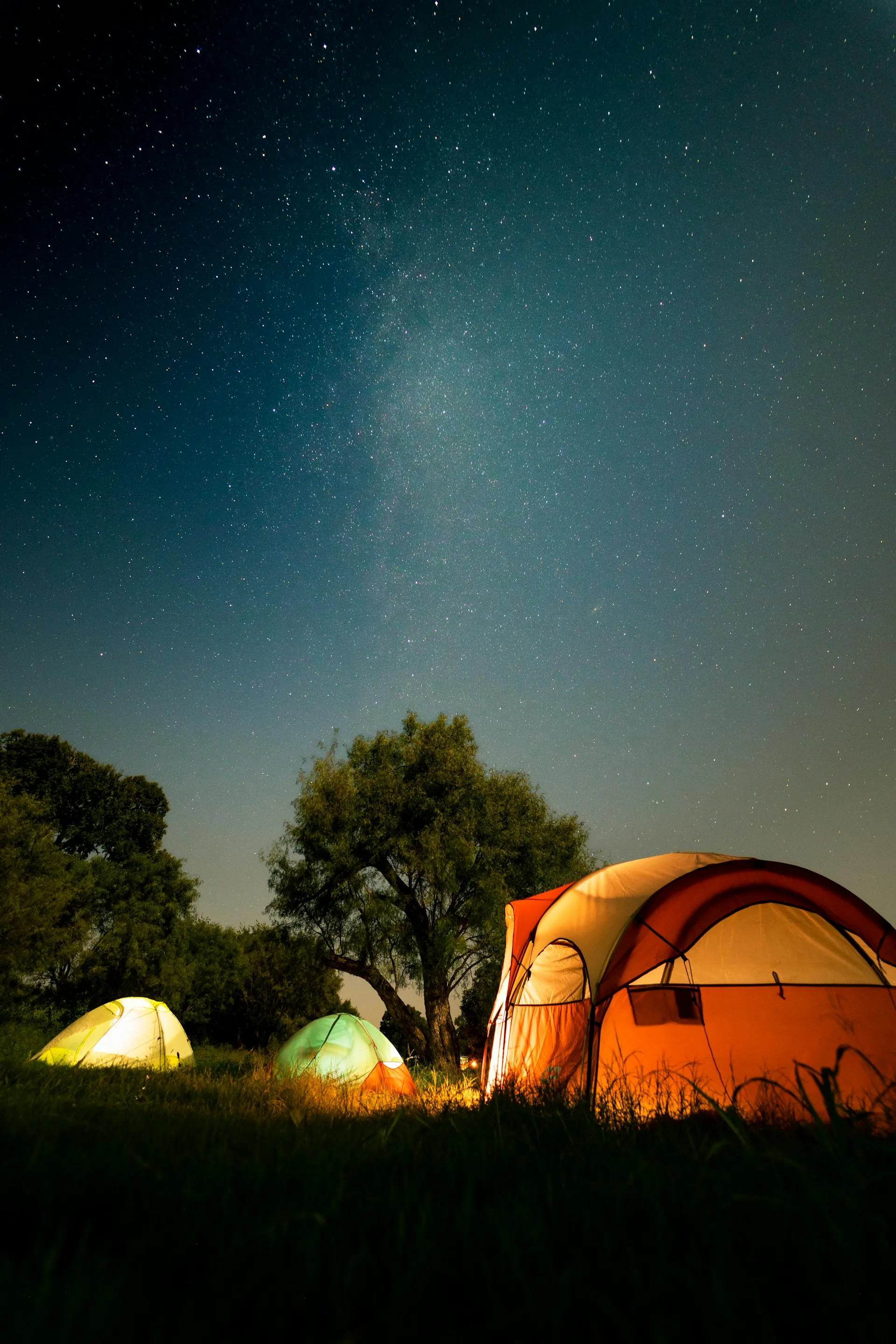 Camping tents illuminated under a starry mountain sky