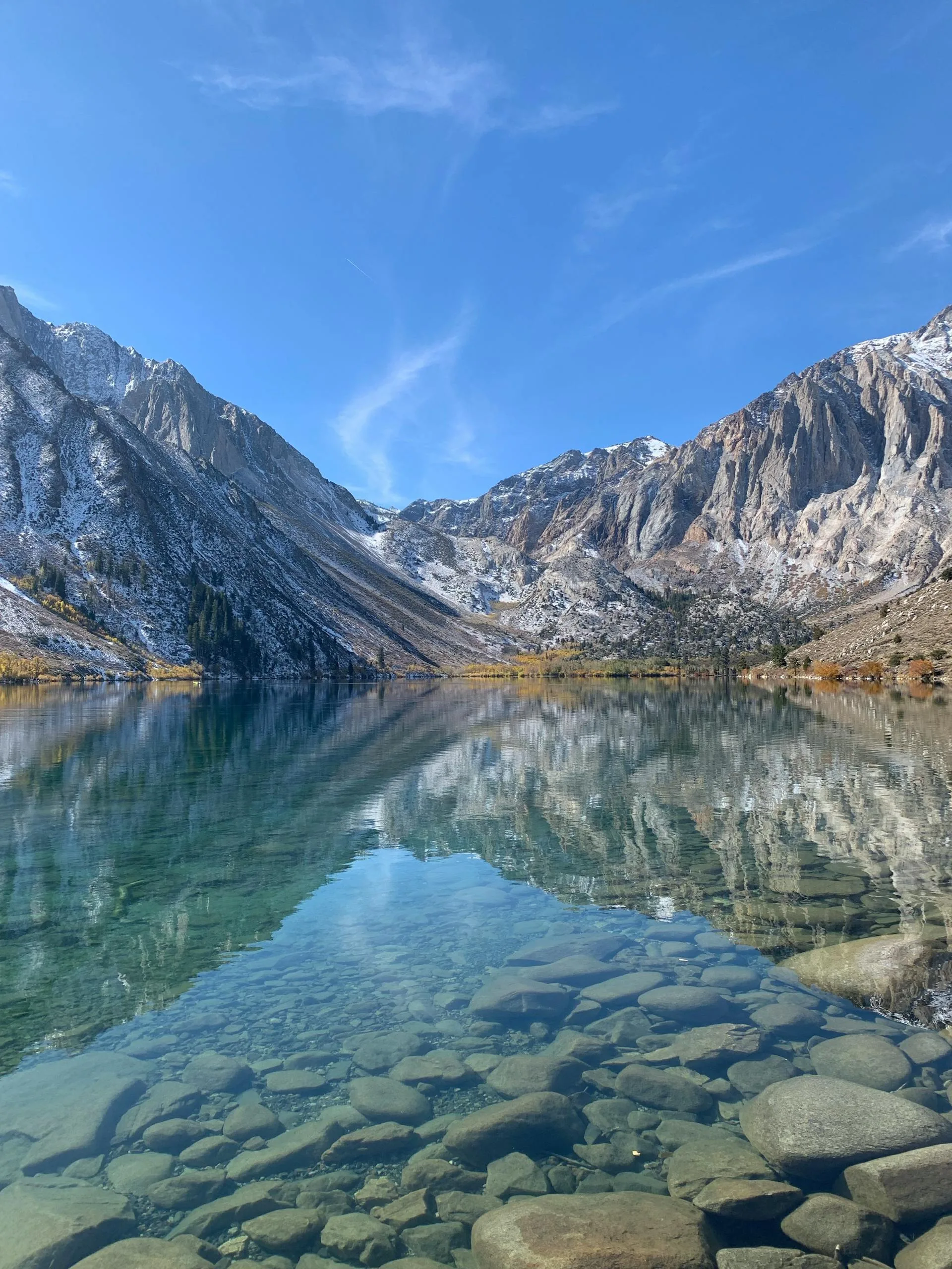 A calm lake near mountains under a bright blue sky