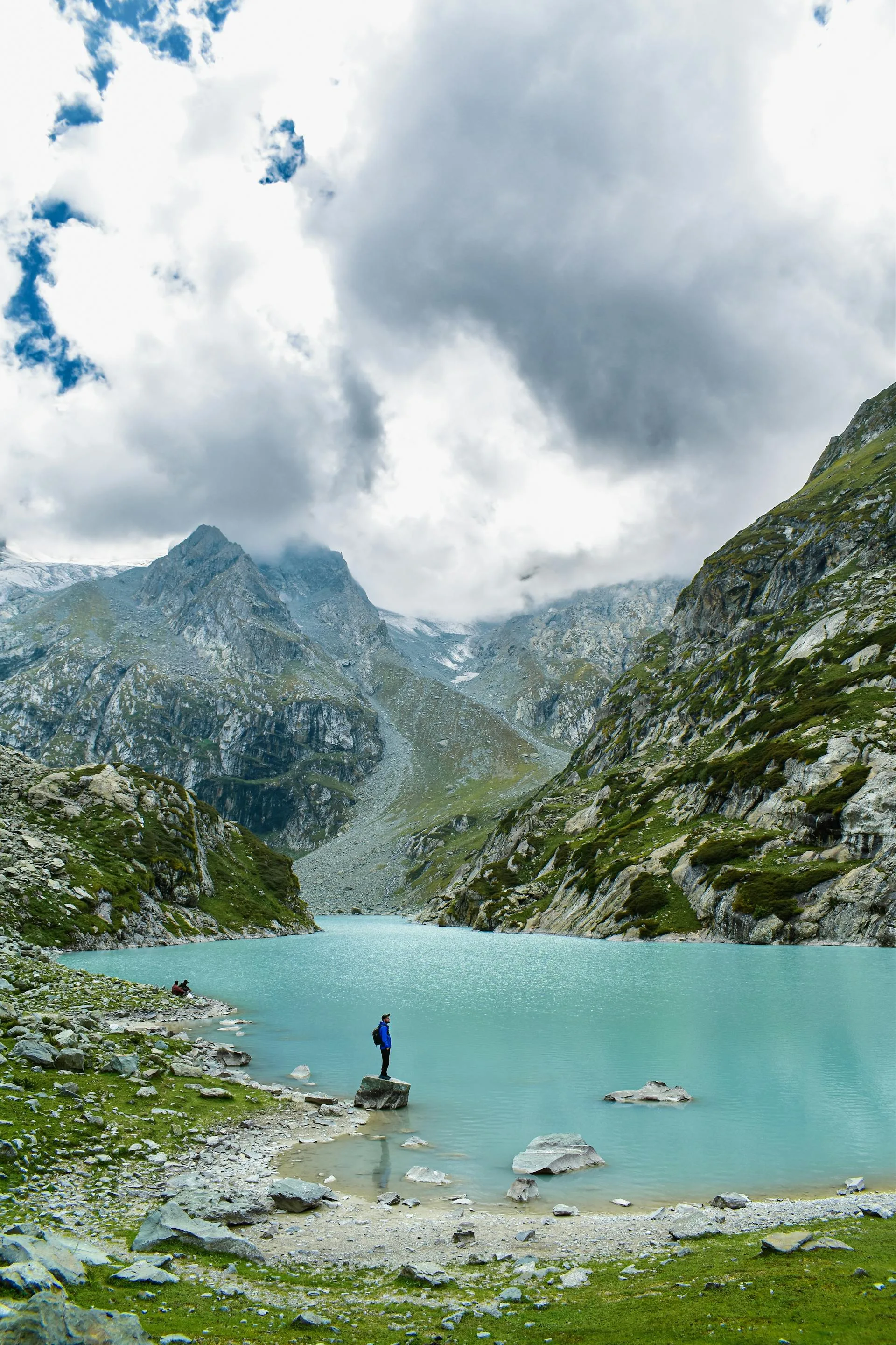 A turquoise alpine lake surrounded by mountains and dramatic skies