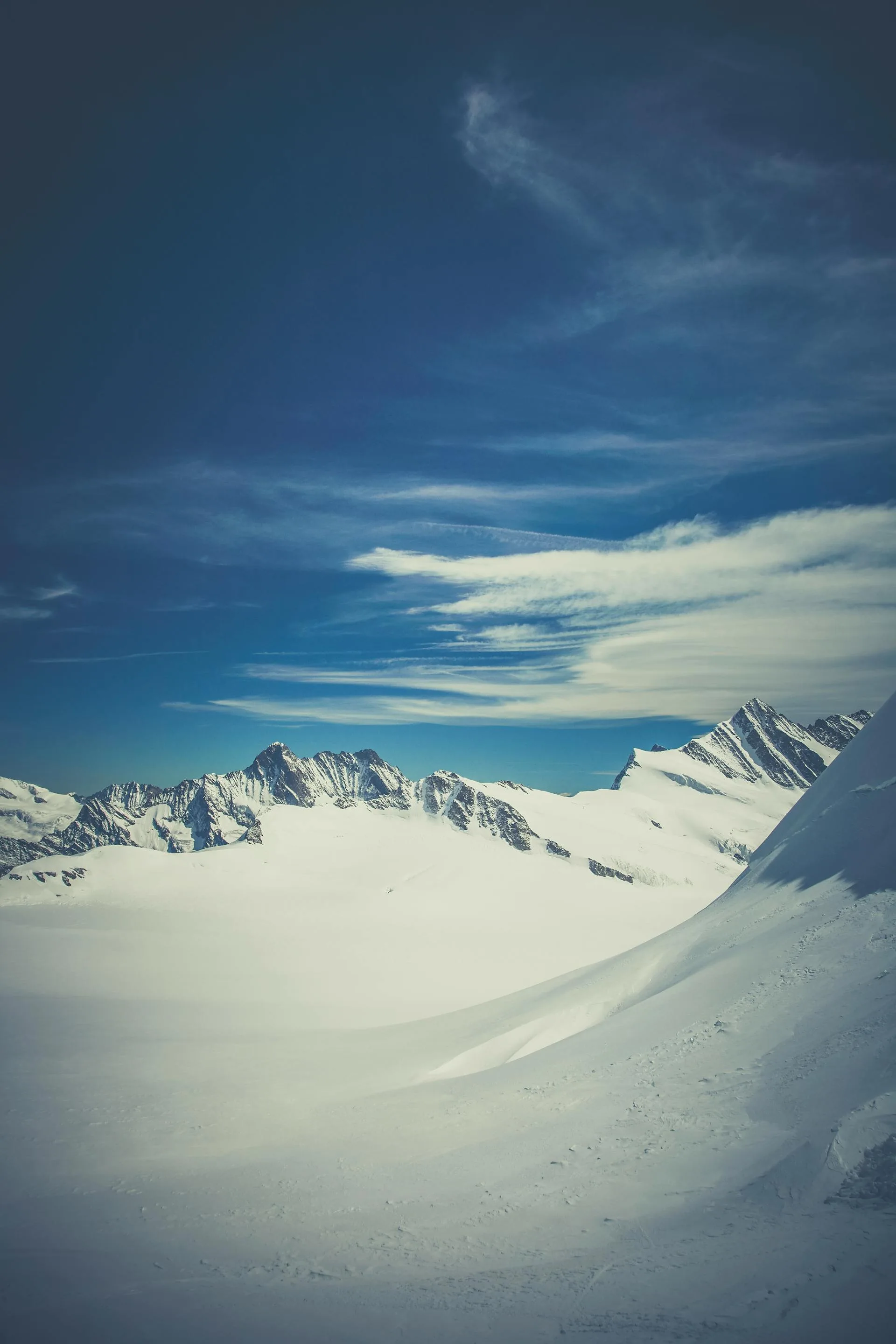 A massive glacier with snow-capped mountains under clear blue sky